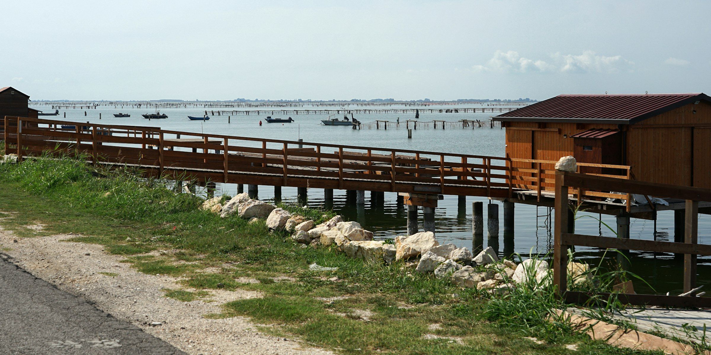 Un pontile di legno e barche ormeggiate sull'acqua del delta del Po, a Porto Tolle.