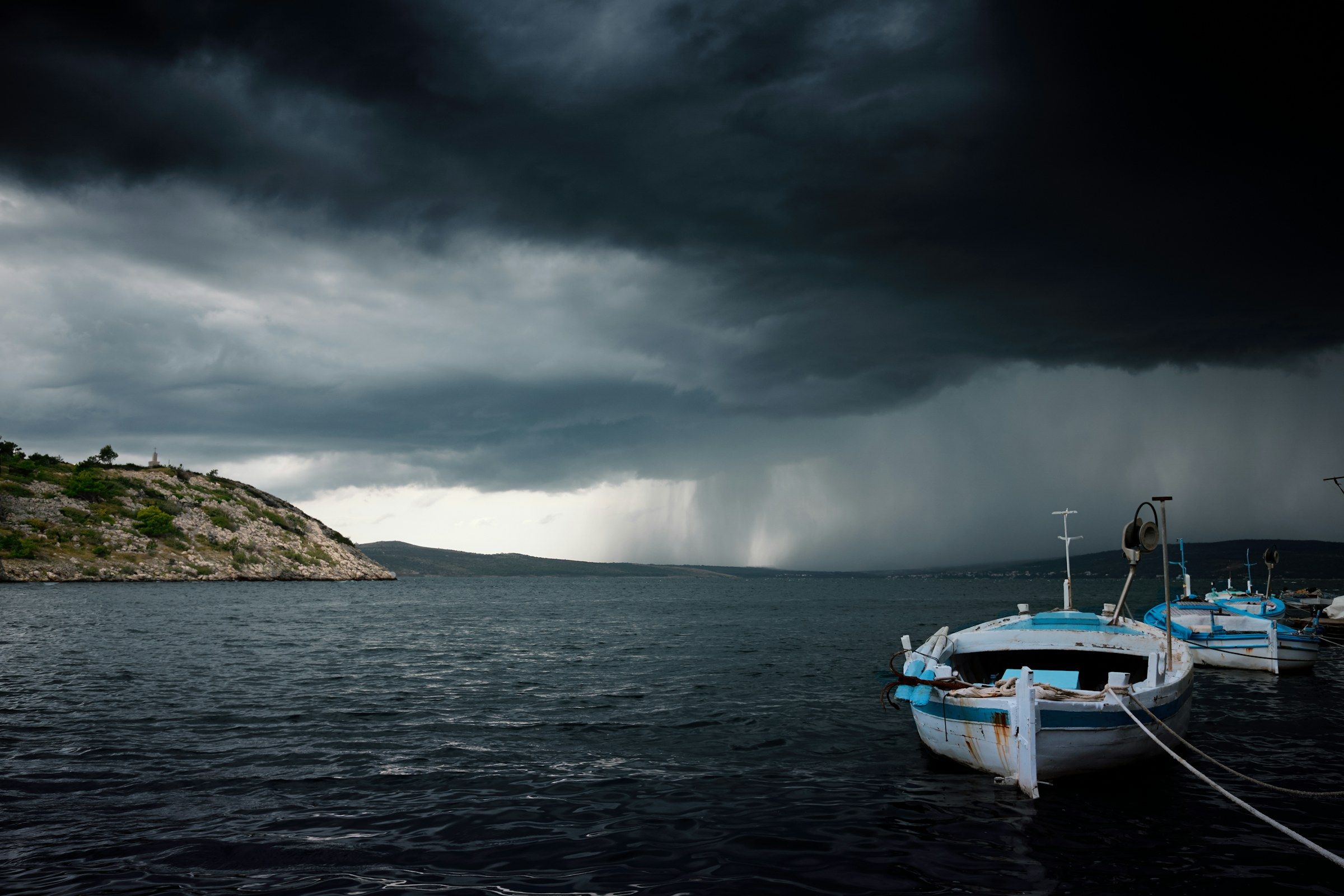 Nuvole di temporale scure sopra una baia con le barche ormeggiate.